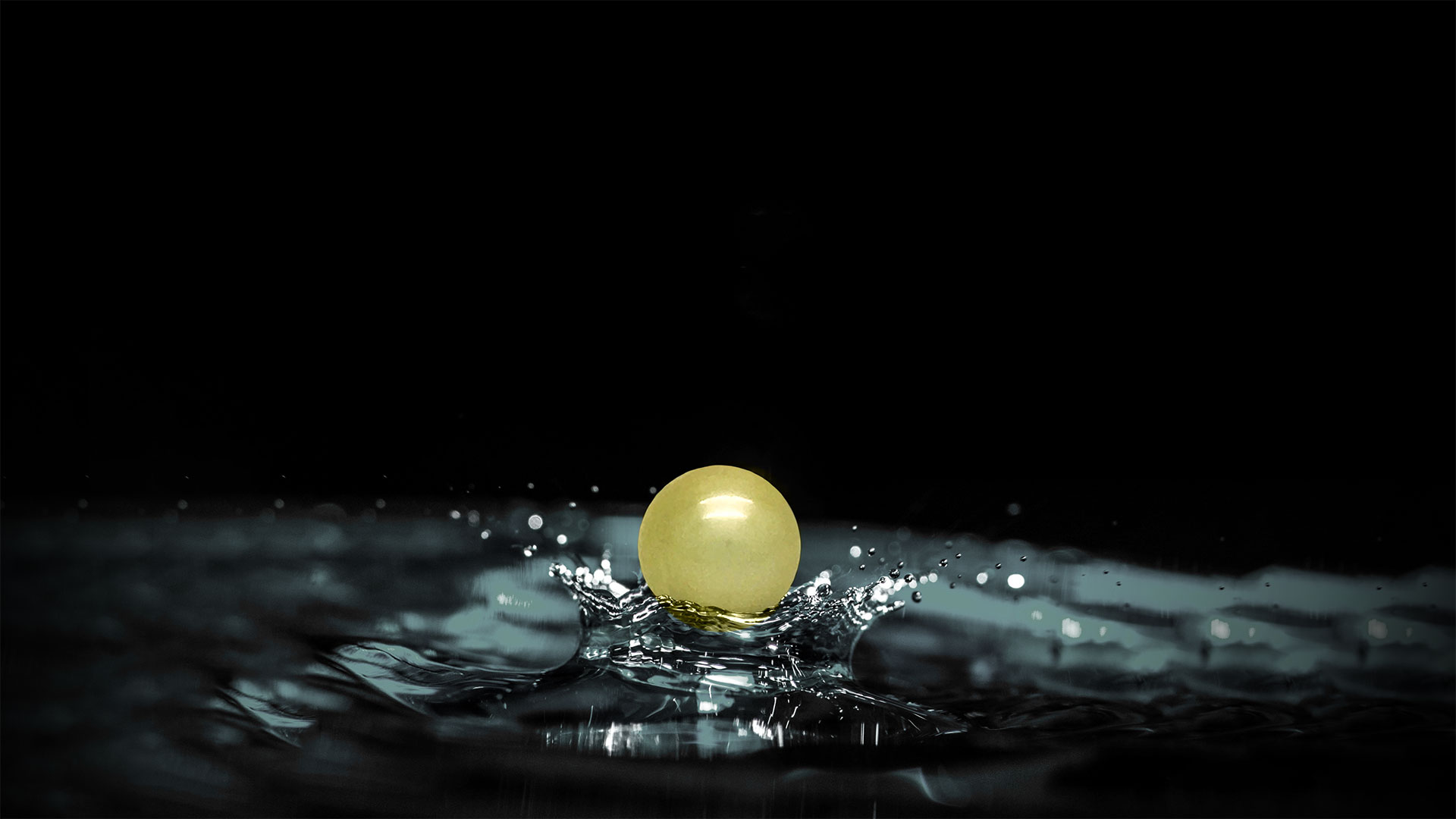 Una perla tahitiana dorada cayendo sobre el agua